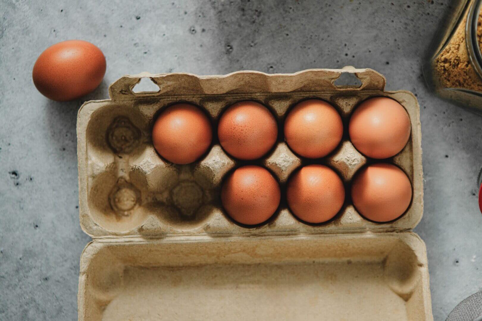 Carton with brown eggs on gray surface