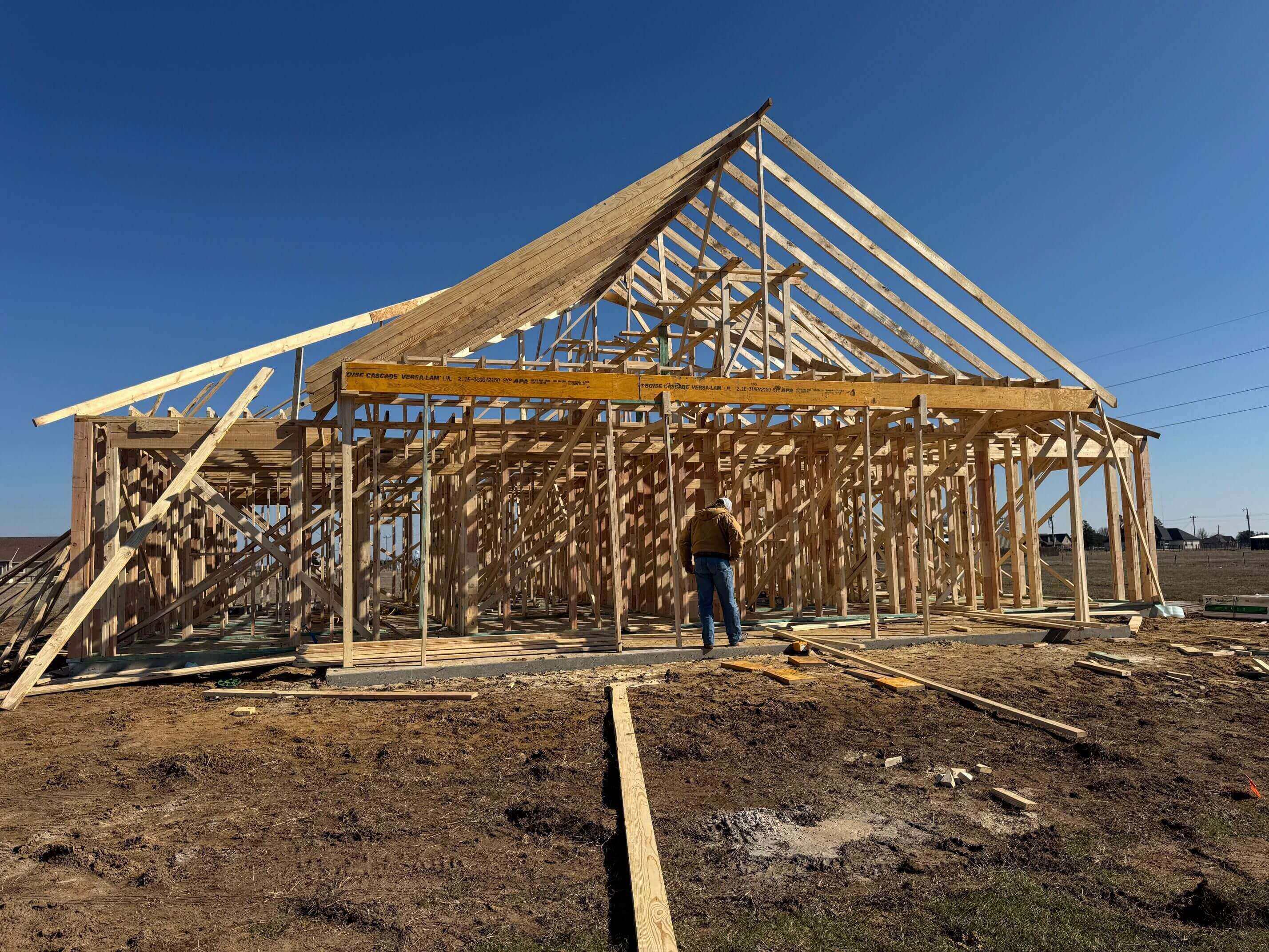 Wooden house frame under construction with worker