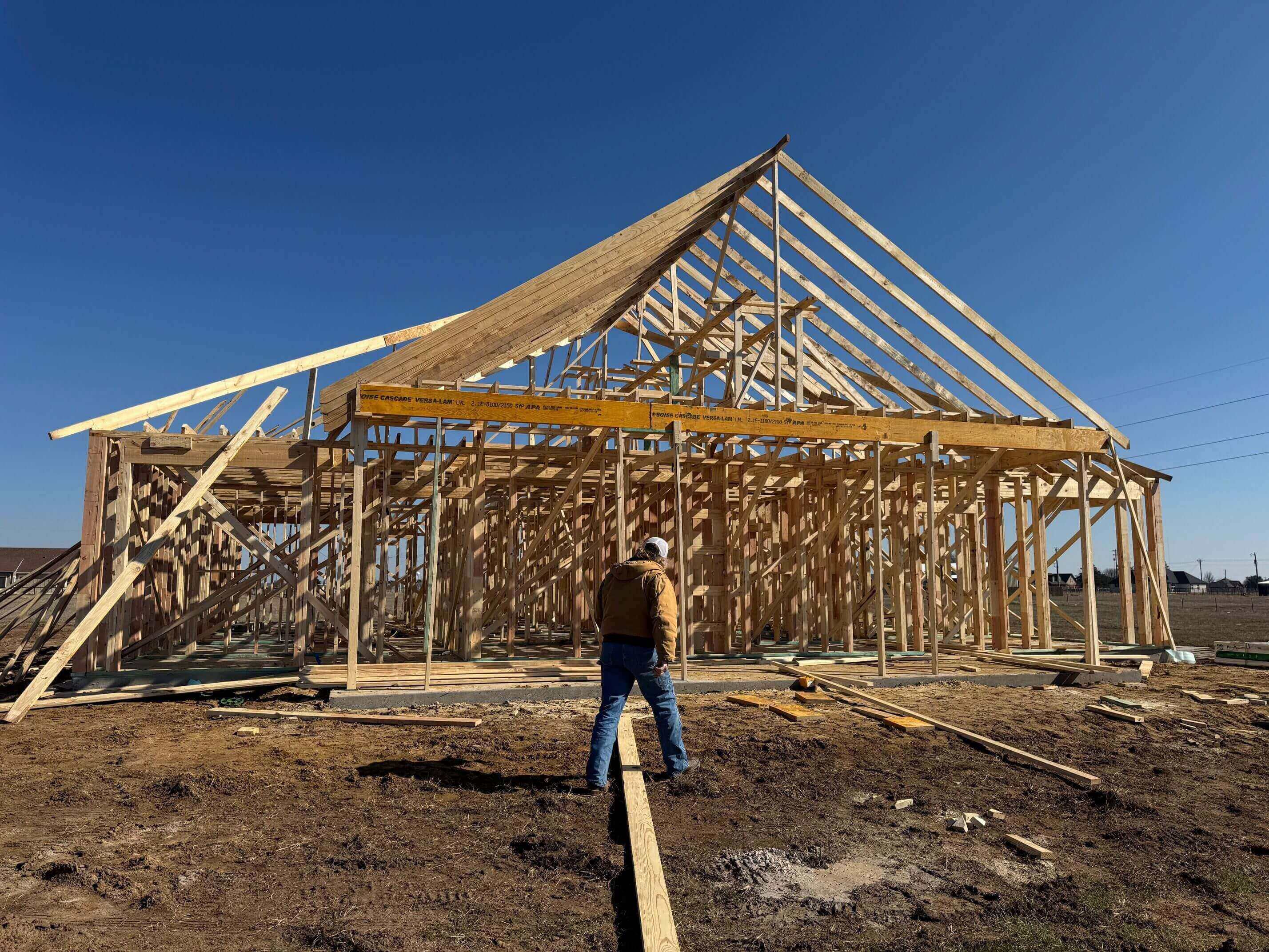 Worker at wooden house frame construction site